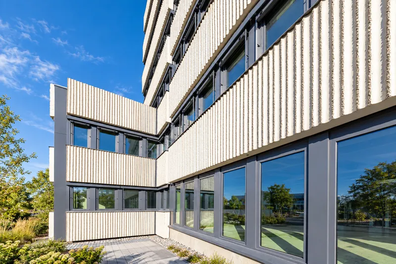 Angle du bâtiment avec panneaux striés et grandes fenêtres au rez-de-chaussée